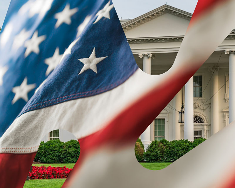 Det hvite hus i Washington D.C. med et amerikansk flagg i forgrunnen som delvis dekker bygningen.